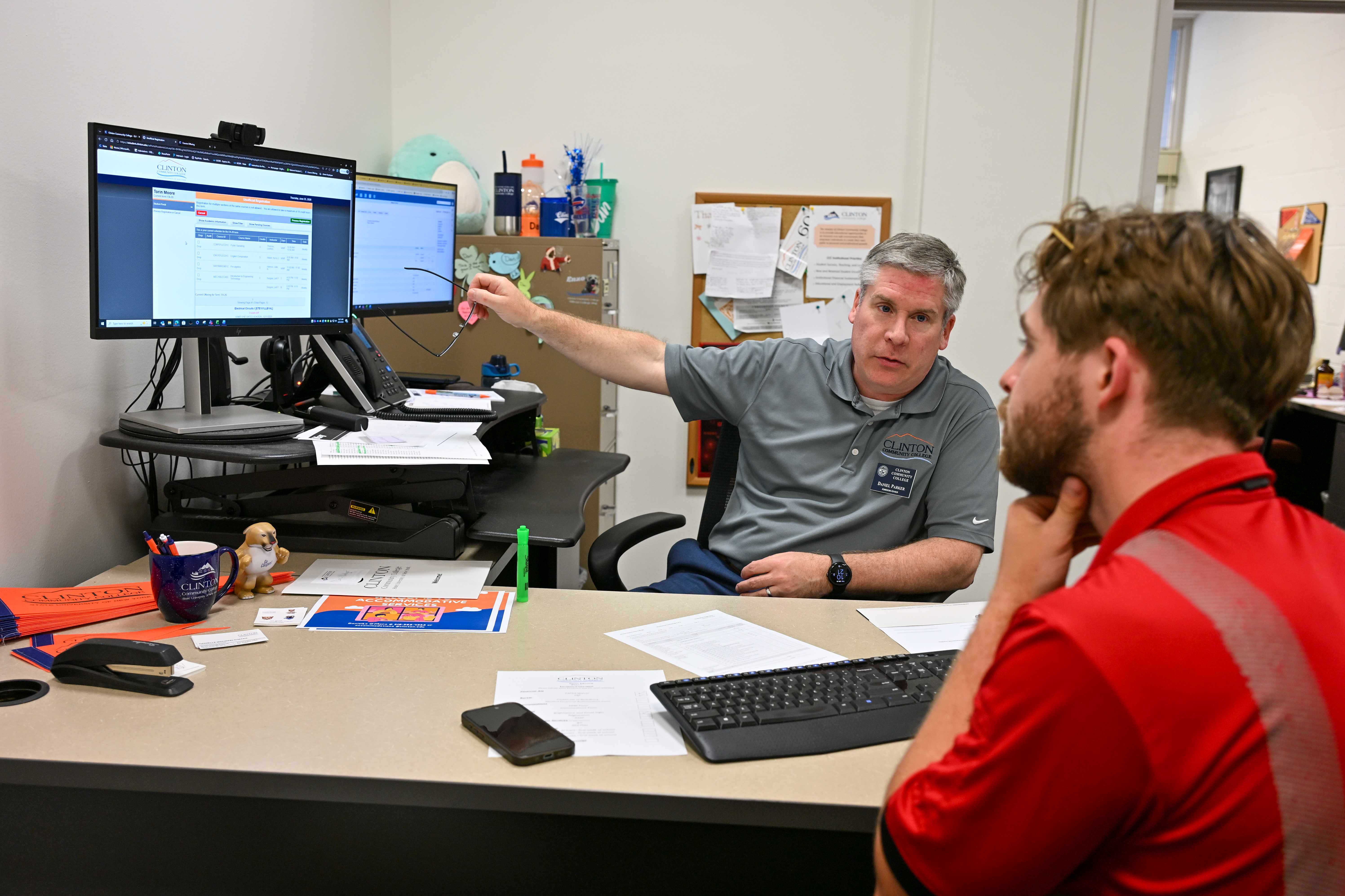 A student working with an admissions advisor at a computer workstation