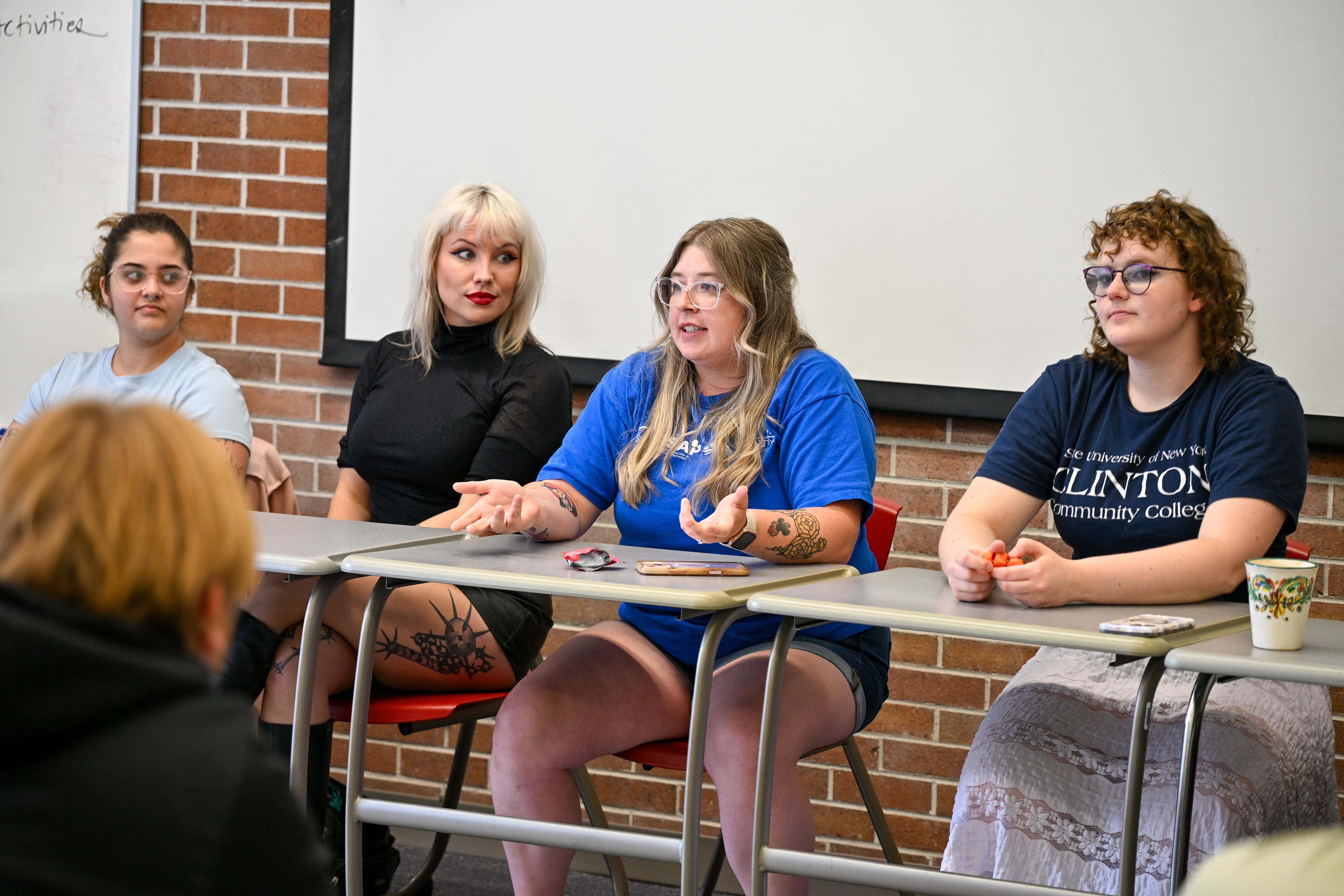 Four students sitting at a table in front of a classroom