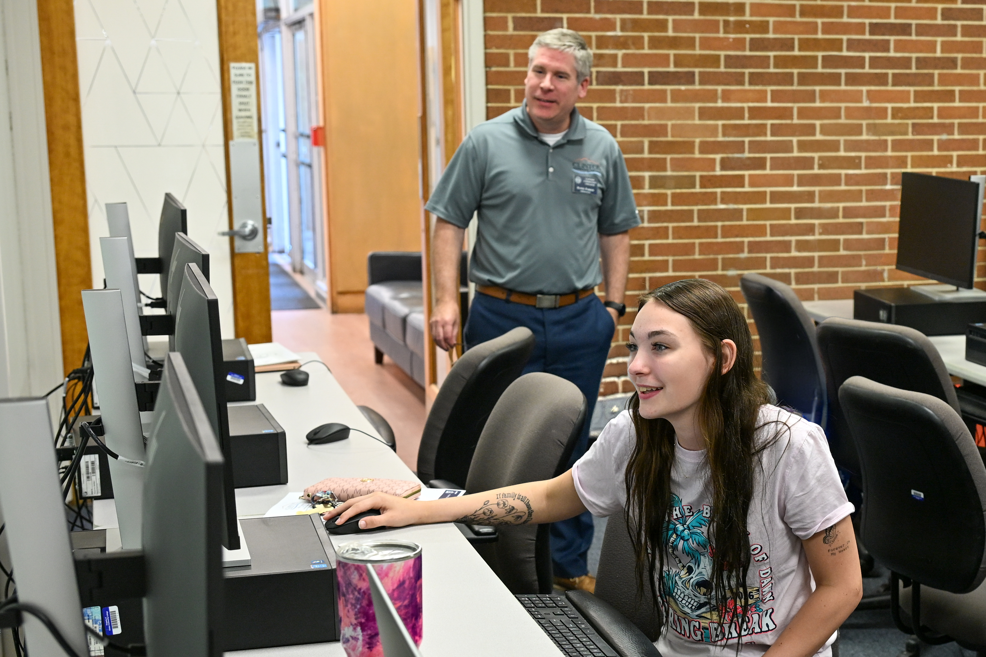 A student working in a computer lab with an admissions advisor nearby